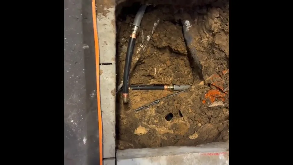 Opened concrete slab and under-floor pipe repair area for Restored basement after burst repair